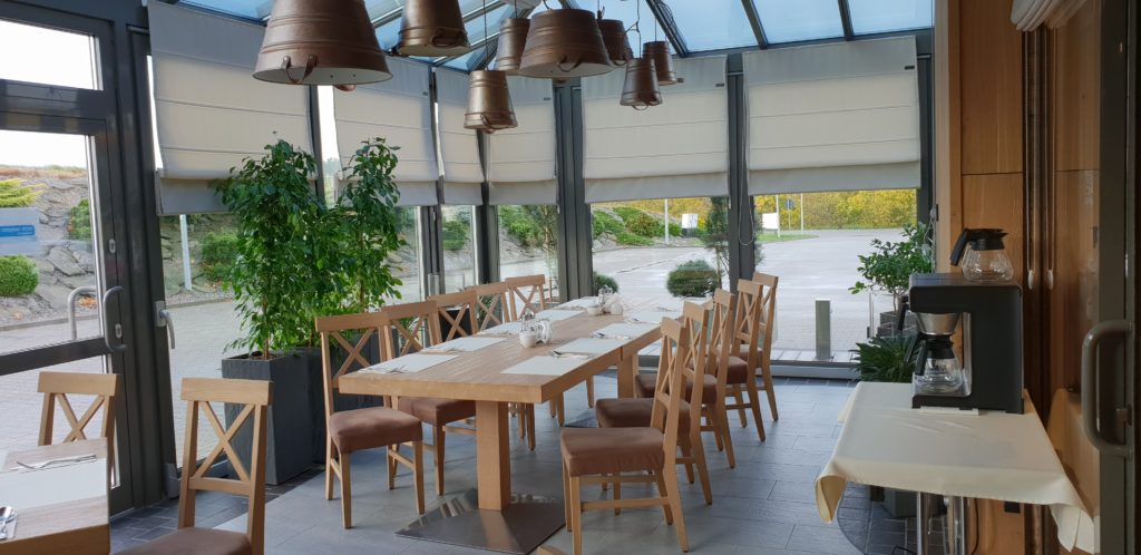 Beżowe rolety rzymskie wiszące na dużych oknach w restauracji