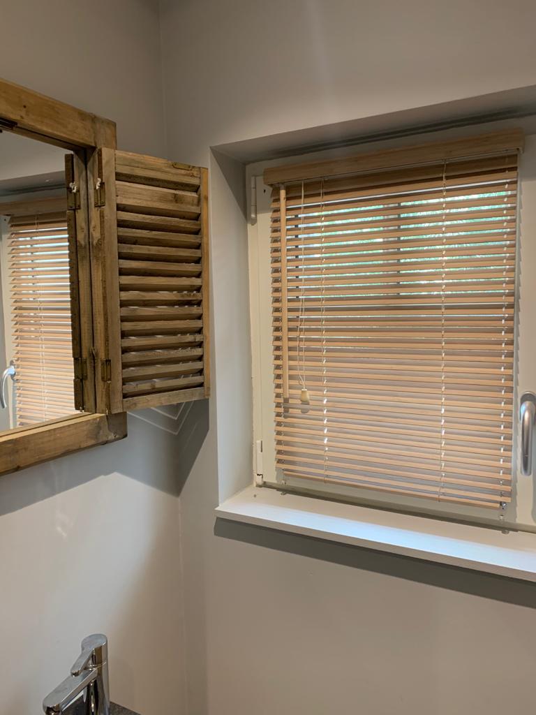 Zdjecie pokazuje żaluzję drewnianą 25mm zamontowaną na oknie w łazience